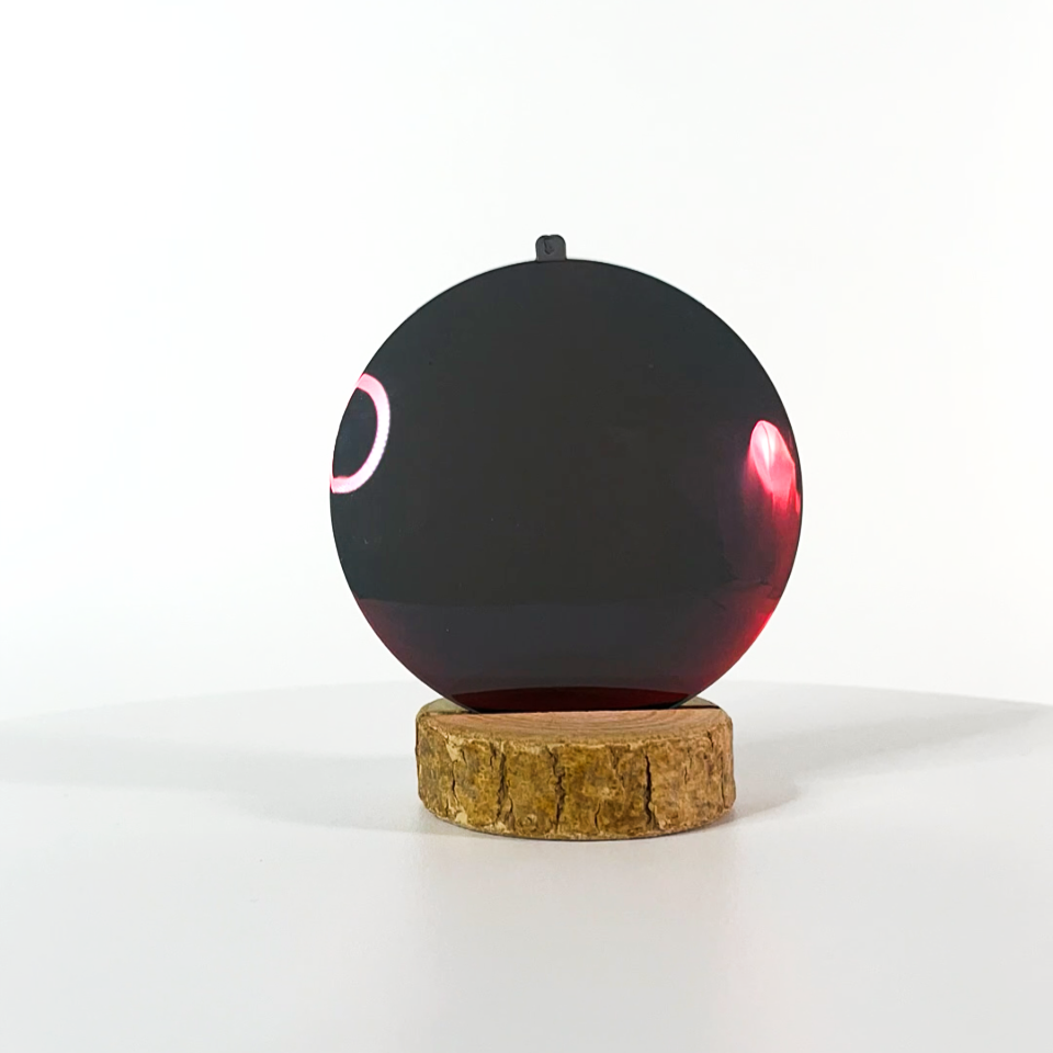 Verre de lunettes de soleil rouge polarisé sur un socle en bois et un fond blanc