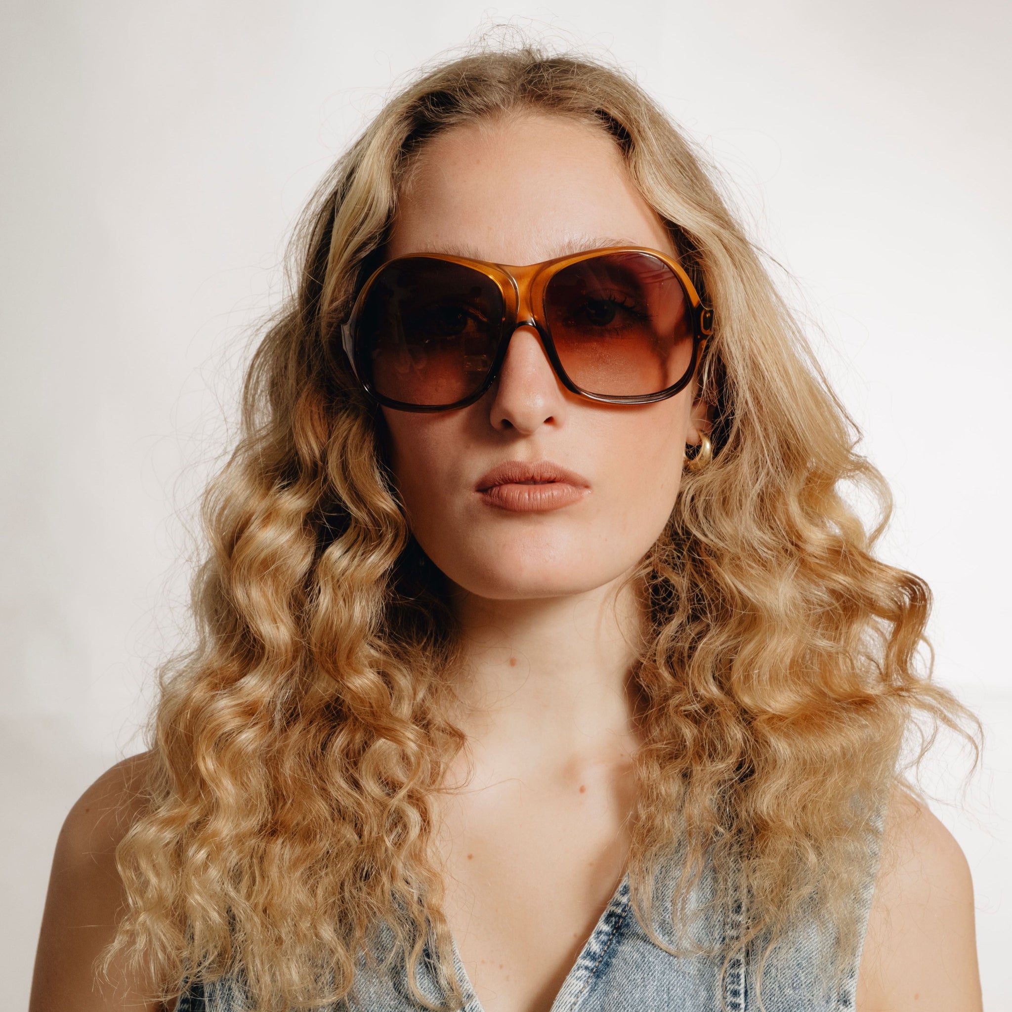 Portrait de femme portant des lunettes vintage Saphira – monture oversize ambrée et verres bruns dégradés, style années 70