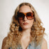 Portrait de femme portant des lunettes vintage Saphira – monture oversize ambrée et verres bruns dégradés, style années 70