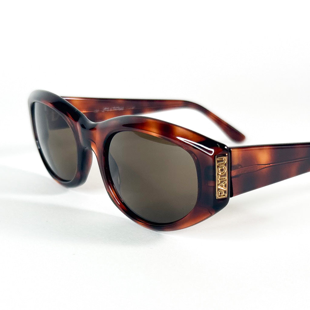 Vue de 3/4 des lunettes Jean Patou – logo doré sur branche, monture en acétate écaille