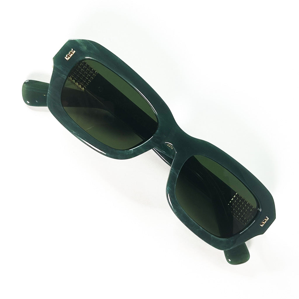 gros plan sur la forme rectangulaire géométrique en acétate vert marbré, verres vert foncé et petite étiquette dorée LANVIN sur la face