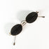  vue de dessus d’une paire de lunettes Paco Rabanne en métal doré, verres ovales noirs, branches croisées sur fond blanc