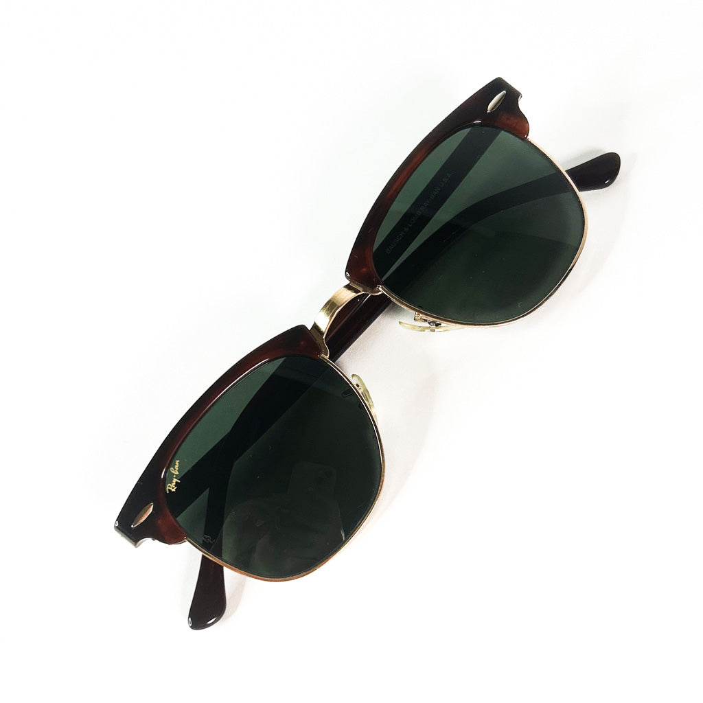 Lunettes Ray-Ban Clubmaster USA dépliées, vue en plongée sur fond blanc mettant en évidence les verres verts et la monture écaillée