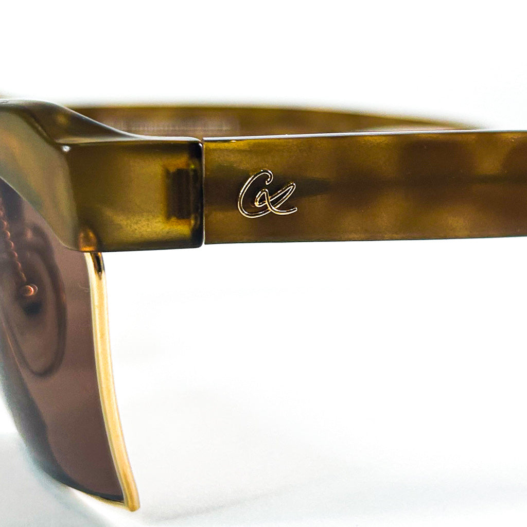 Zoom sur le monogramme doré CL sur la charnière des lunettes Christian Lacroix