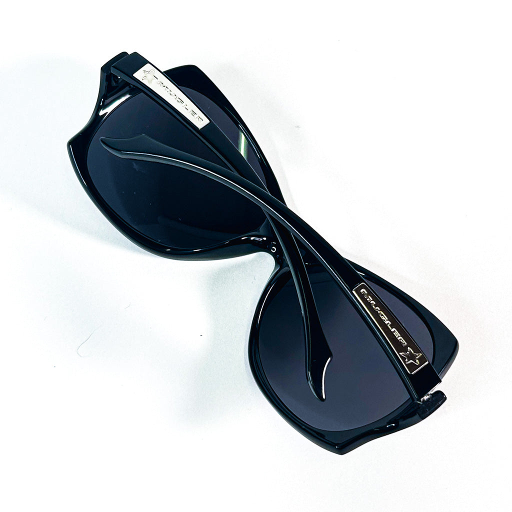 Lunettes de soleil Mugler TM10183 C1 pliées, vue en plongée sur les branches croisées et le logo étoile