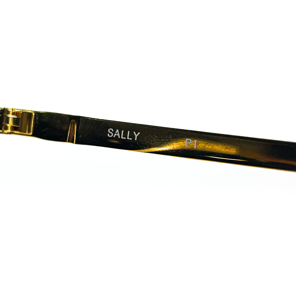 	Lunettes de soleil Nouvelle Vague Sally P1 – gros plan gravure “SALLY P1” sur branche métallique dorée, style futuriste monoverre