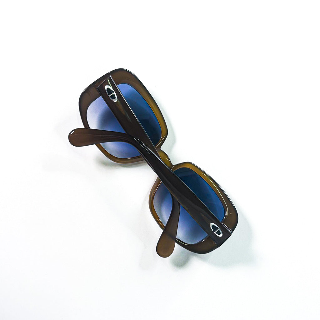 Vue plongeante des lunettes pliées, montrant les branches croisées et les logos Dior en métal