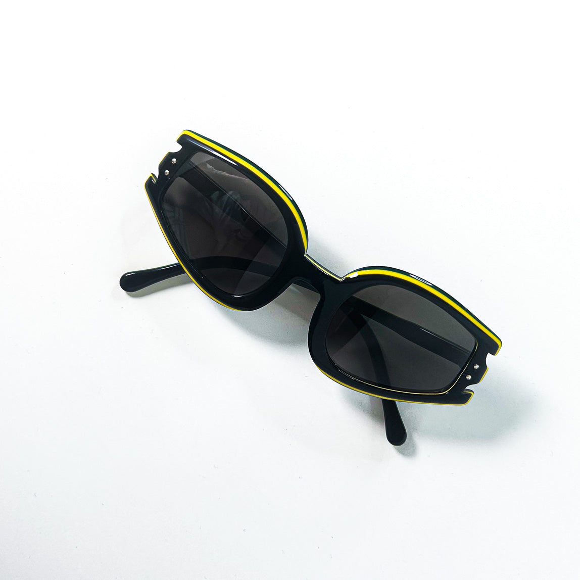 Lunettes de soleil vintage noires et jaunes – vue de trois-quarts face posée à plat