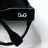 Détail du logo métallique D&G sur la branche des lunettes de soleil noires.