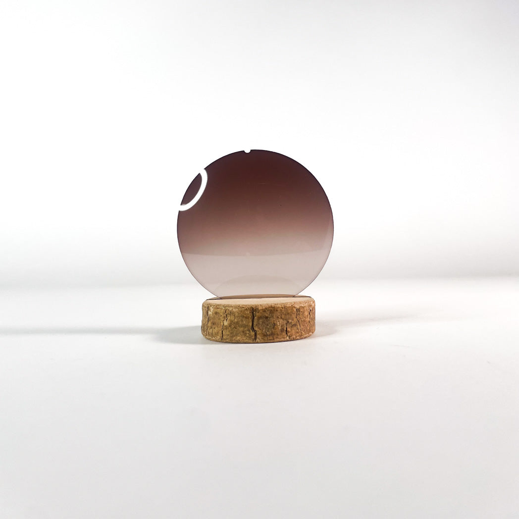 Verre de lunettes de soleil marron bidégradé sur un support et fond clair