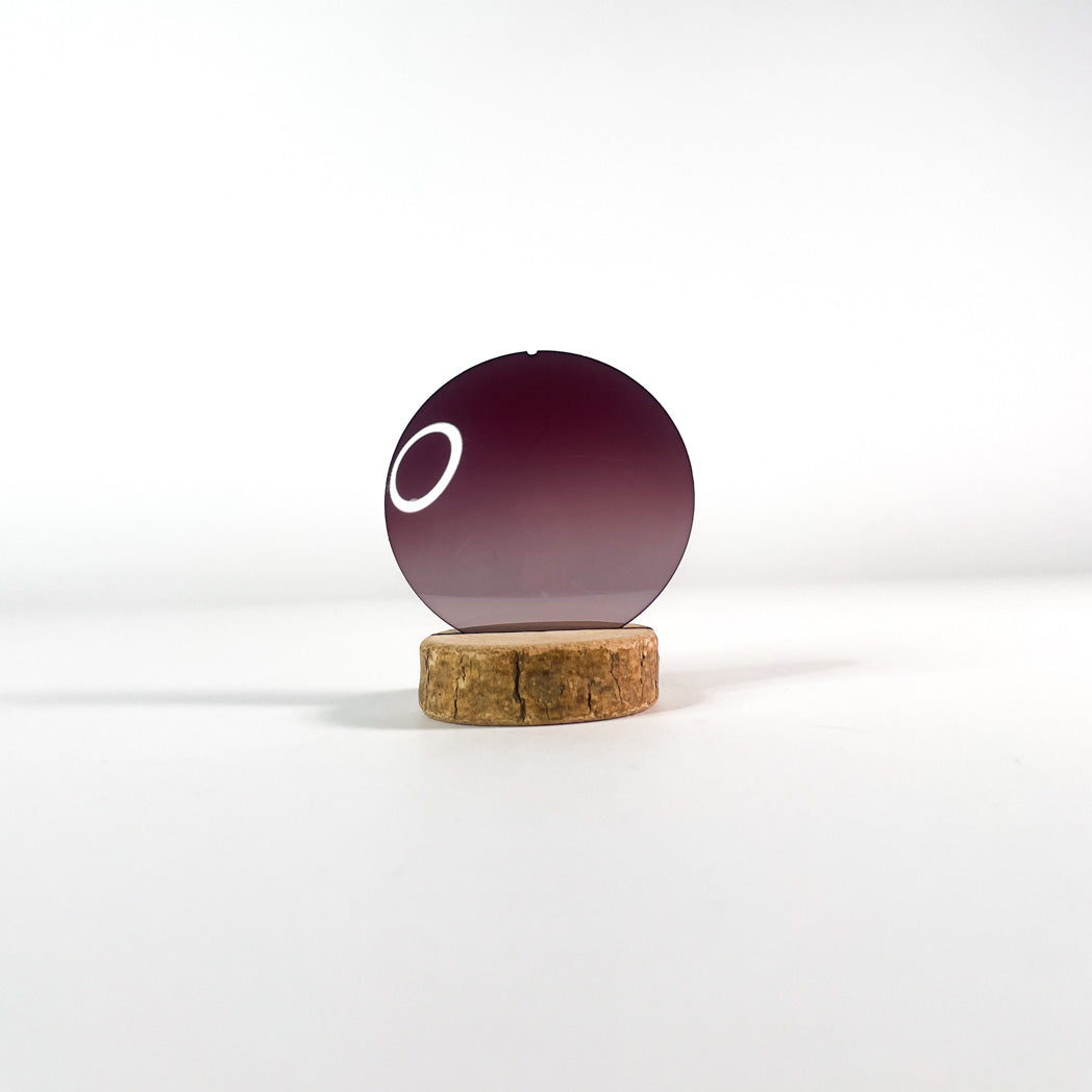 Verre de lunettes de soleil bordeaux dégradé sur un support en bois
