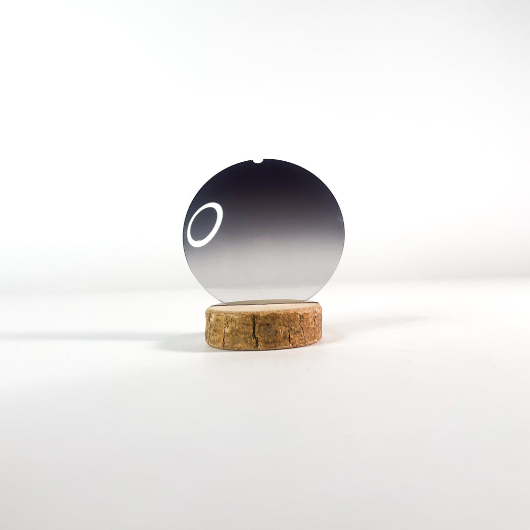Verre de lunettes de soleil noir bidégradé sur support et fond blanc