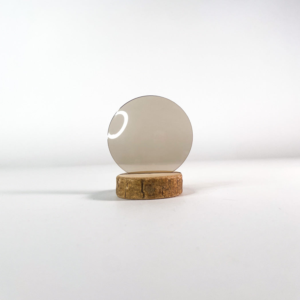 Verre de lunettes de soleil brun clair, socle en bois et arrière-plan blanc