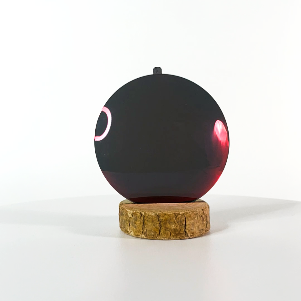 Verre de lunettes de soleil rouge polarisé sur un socle en bois et un fond blanc
