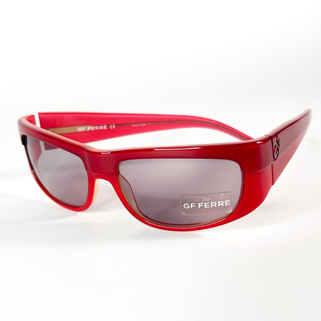 Gros plan sur la branche gauche des lunettes de soleil Gianfranco Ferré rouges, avec détails du logo et charnière