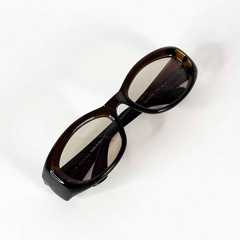 Détail du logo Gucci argenté sur la branche gauche d’une paire de lunettes vintage