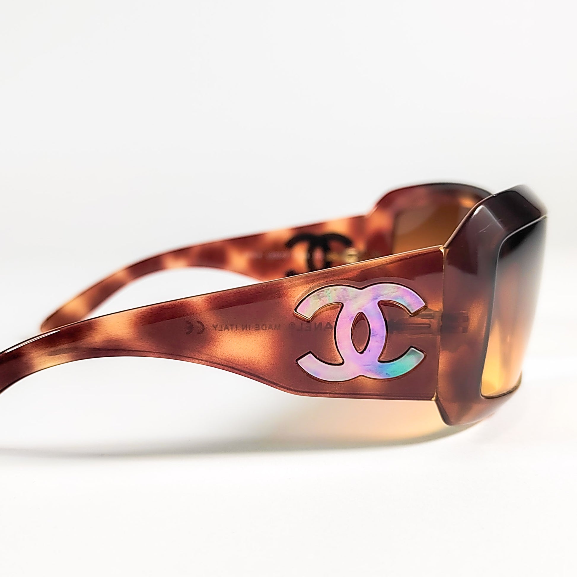 Gros plan branche Chanel 5076-H, CC ajouré révélant la plaque de nacre véritable iridescente.