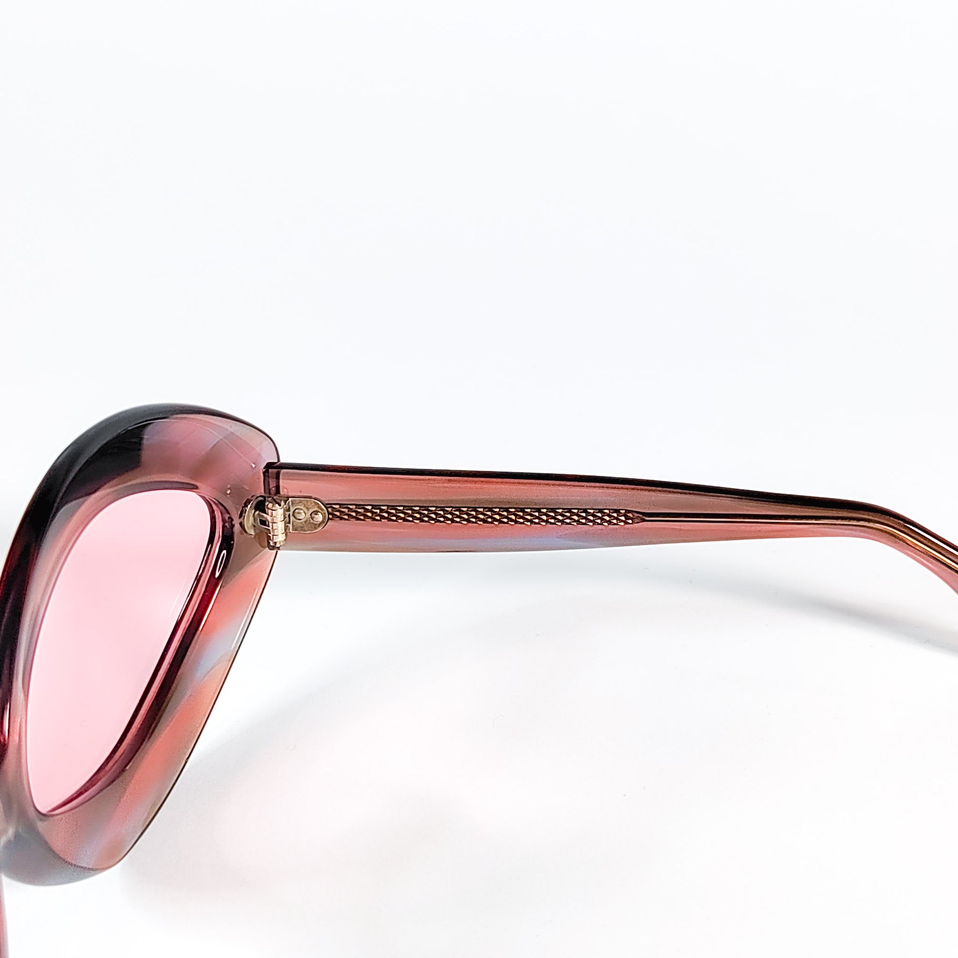 Détail de la charnière dorée et de l'âme métal guillochée des lunettes vintage Sevima en acétate rose